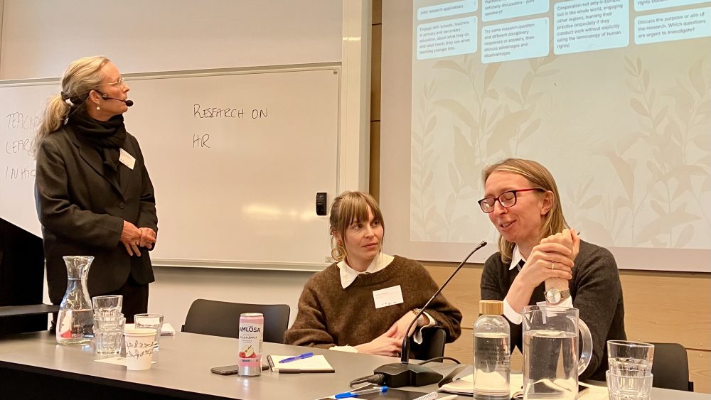 Three women scholars engaged in panel discussion in a conference room.