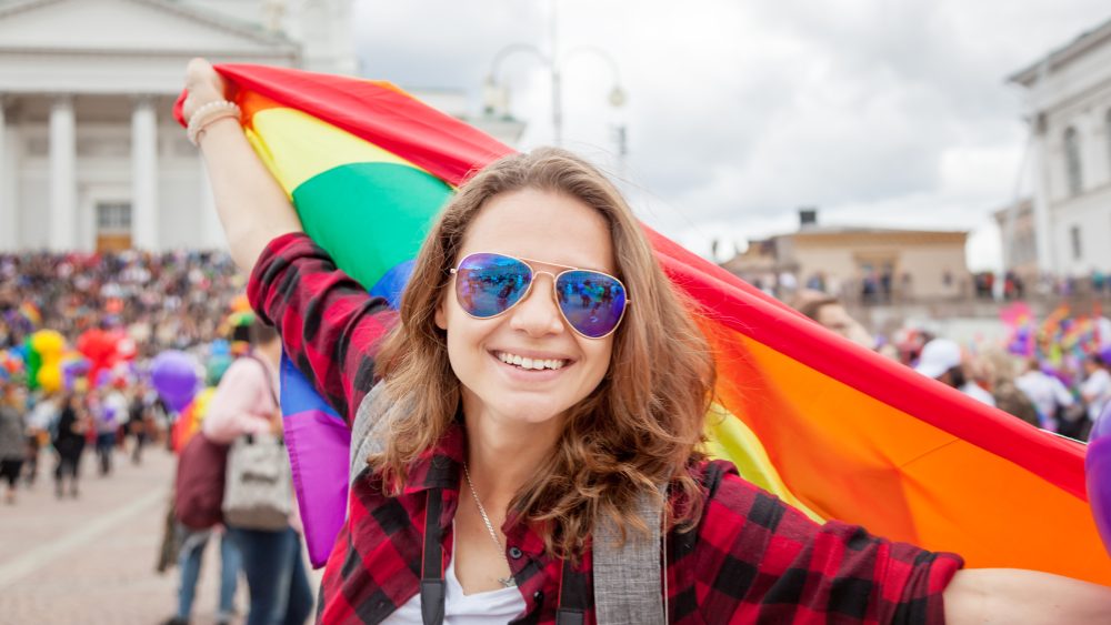 Young happy woman holding a rainbow flag